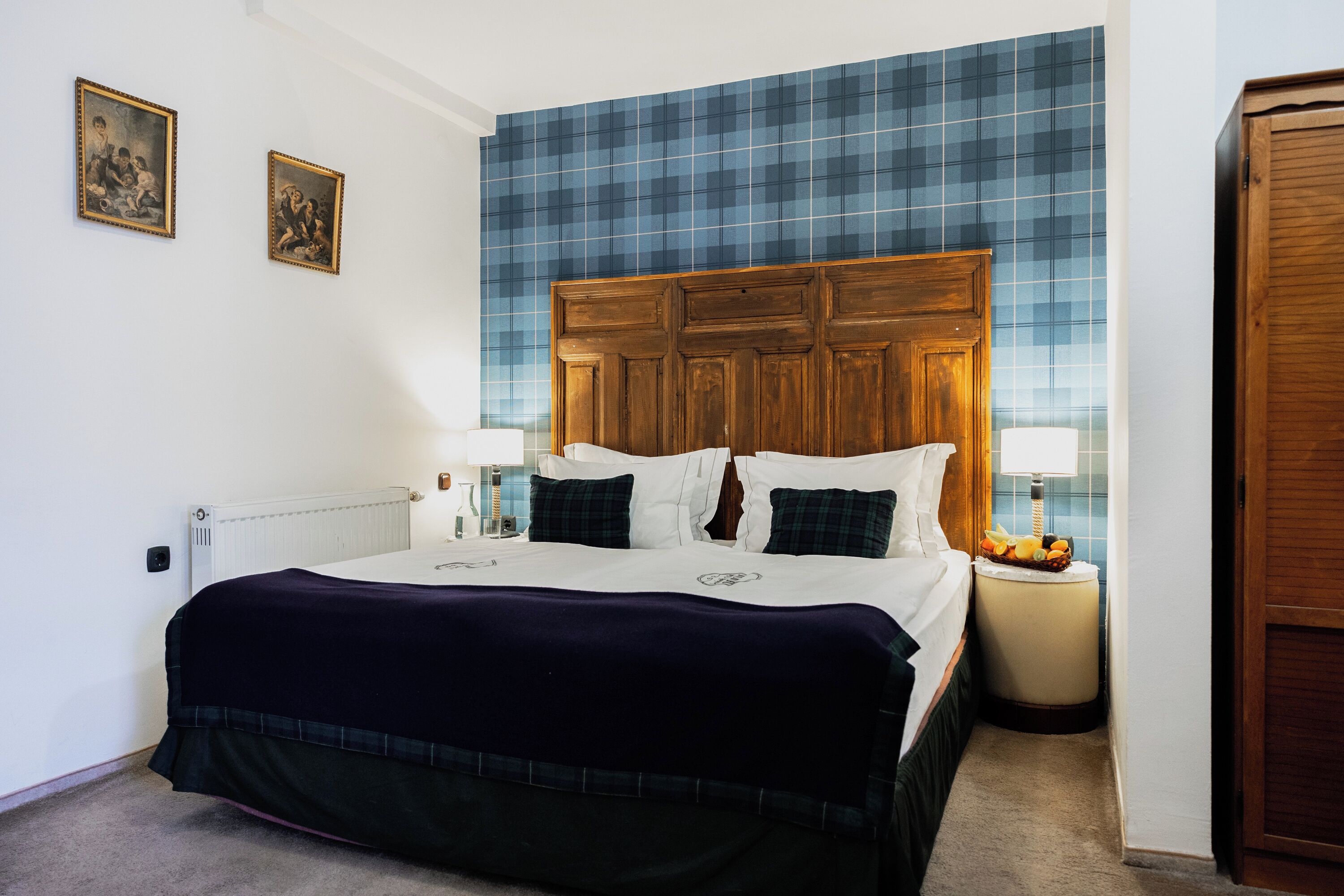 Un dormitorio con una cama grande, dos mesitas de noche, un cabecero de madera y una pared con azulejos azules.