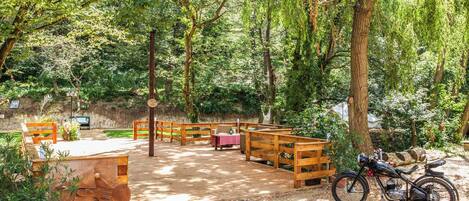 A wooden deck with benches and a table, surrounded by trees.