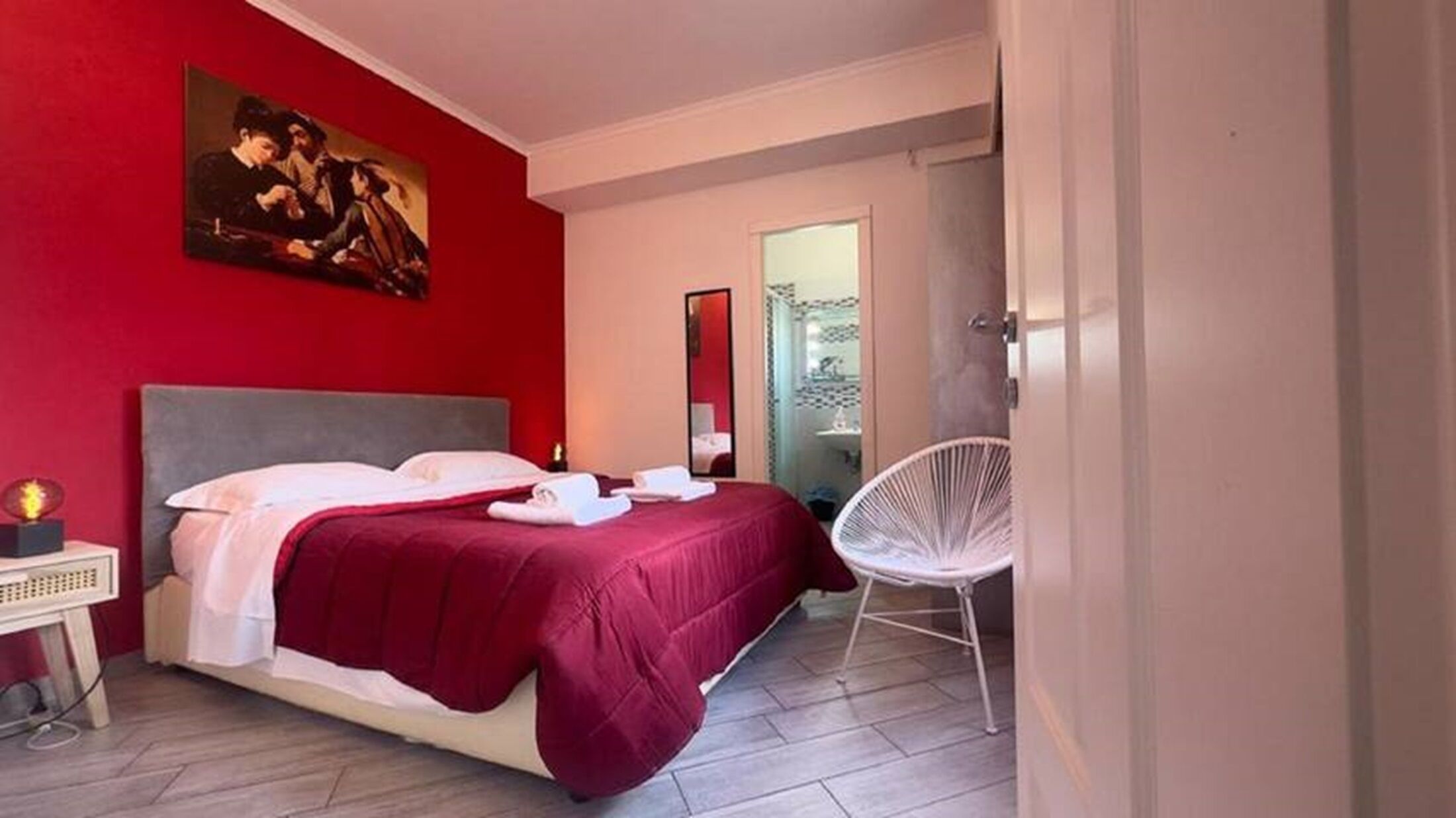 Une chambre à coucher avec un lit, une chaise, un tableau et un miroir.