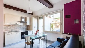 A modern kitchen with white cabinets, a glass dining table, and a black leather sofa. - Rome apartment penthouse with terrace spanish steps trevi fountain barberini (Roma)