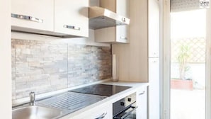 A modern kitchen with a stone backsplash, stainless steel sink, and integrated oven. - Rome apartment penthouse with terrace spanish steps trevi fountain barberini (Roma)