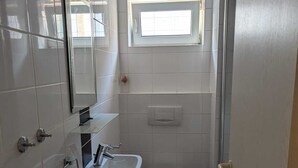 A small bathroom with a sink, toilet, and a window above the toilet.