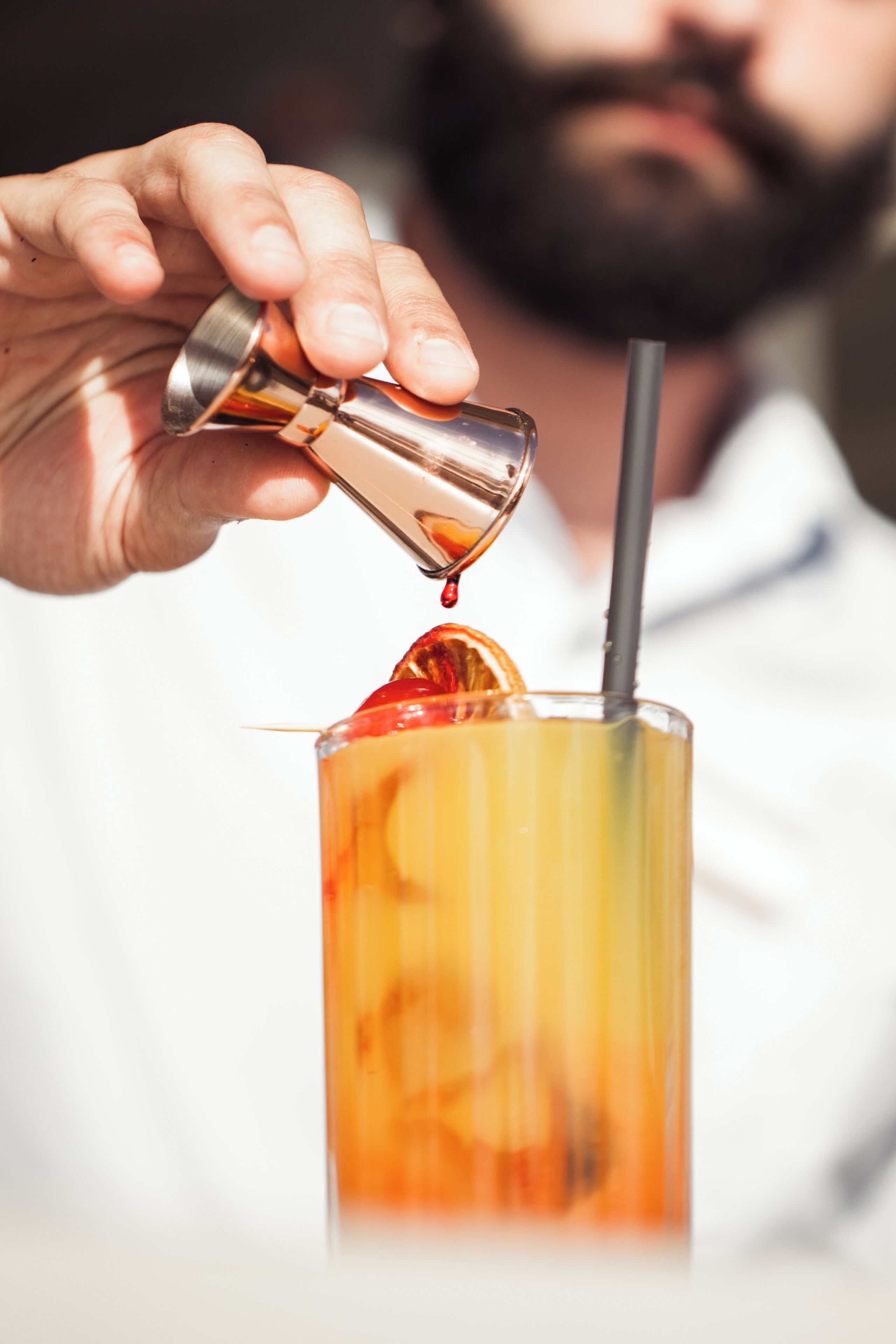 Une personne verse une boisson dans un verre muni d’une paille.