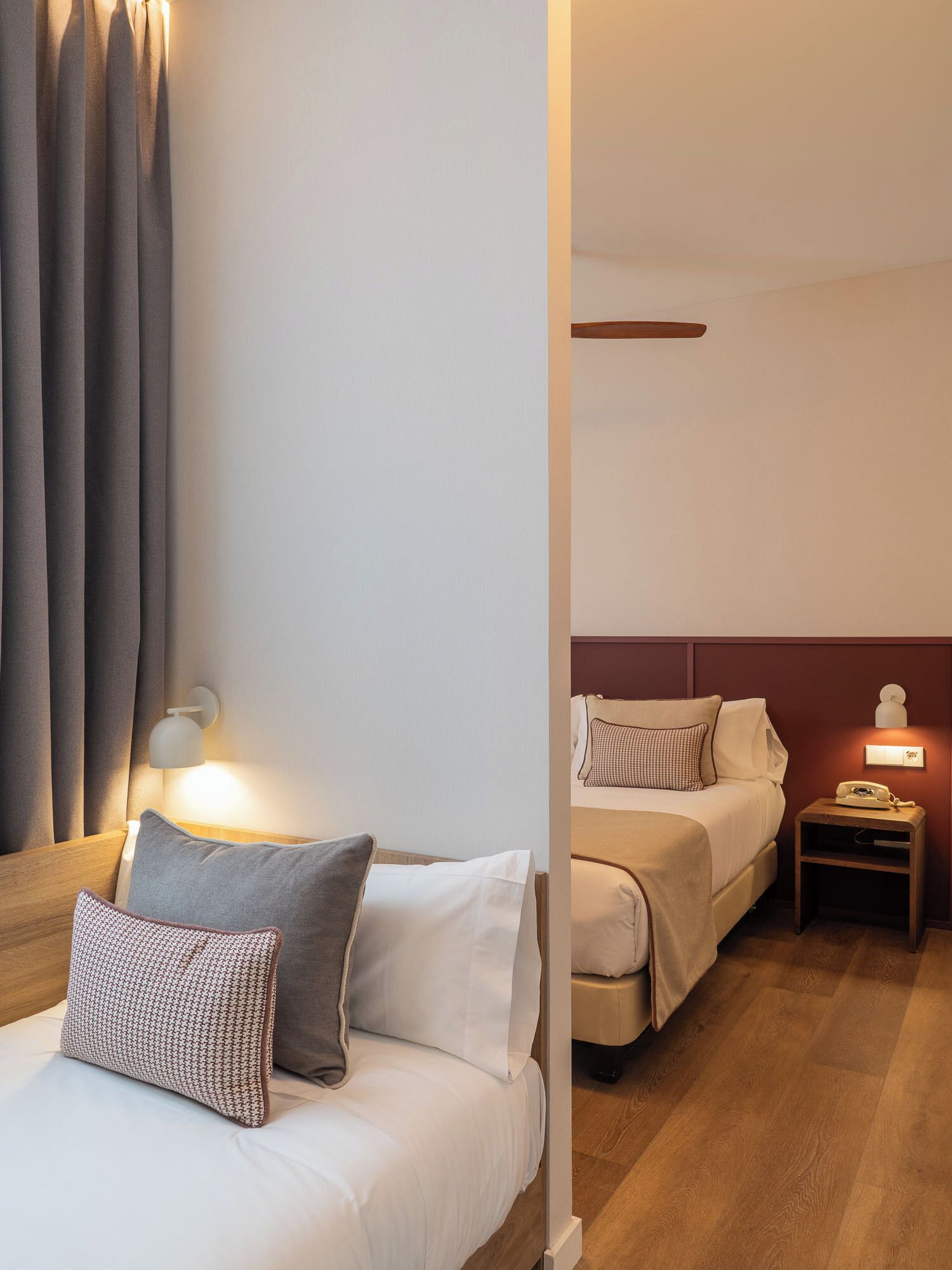 Een hotelkamer met twee bedden, een nachtkastje met een lamp en een wandlamp.