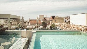 En swimmingpool med klart vand, liggestole og en stenvæg.