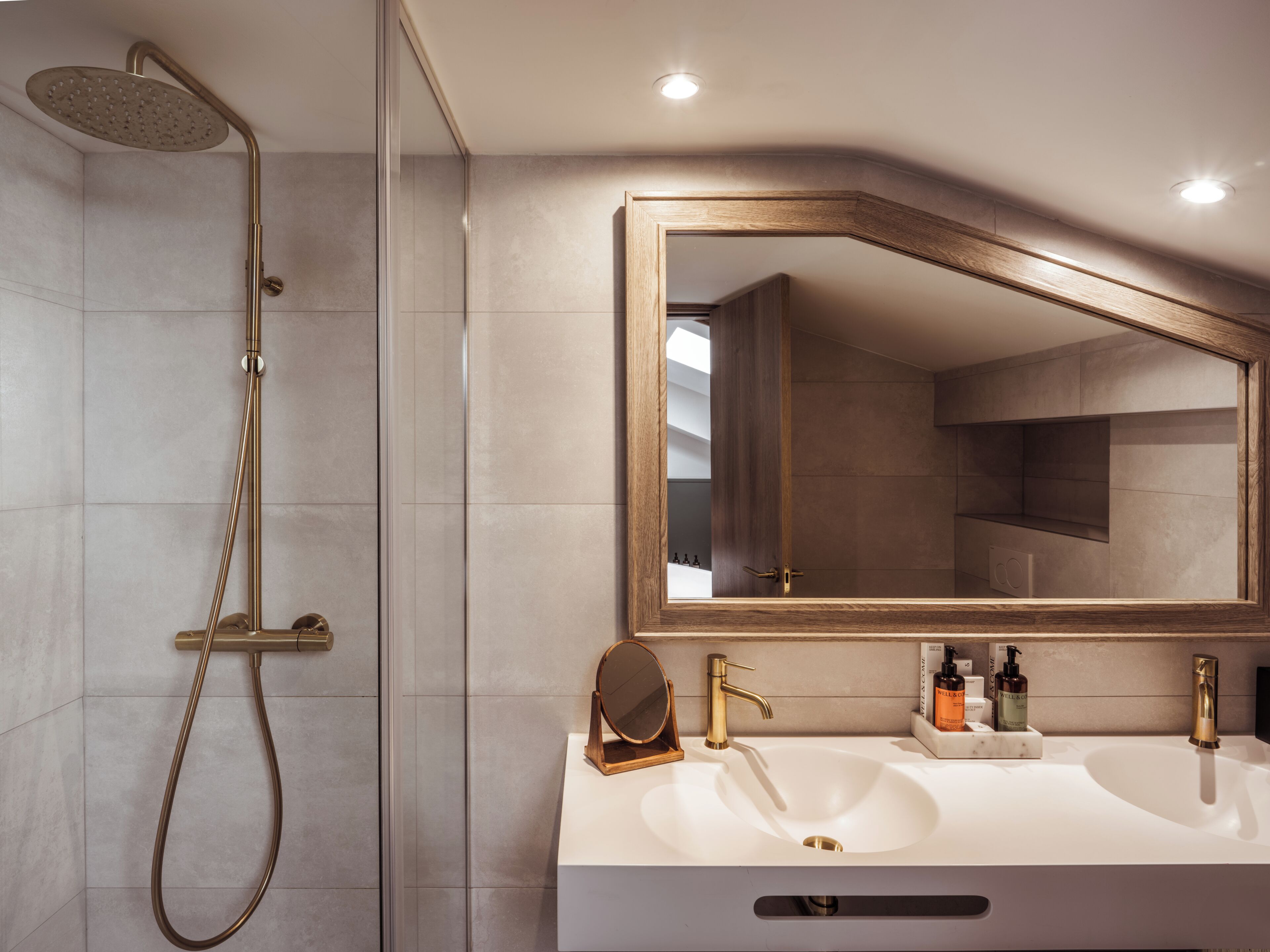 Une salle de bain moderne équipée d’une douche, de deux lavabos, d’un grand miroir et d’un meuble-lavabo en bois.