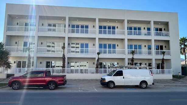 A multi-story building with balconies and a parking area. - Coral Cove (South Padre Island)
