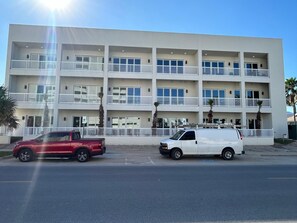 Un edificio de varios pisos con balcones y una zona de estacionamiento.