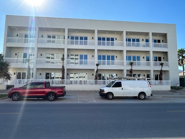 Un edificio de varios pisos con balcones y una zona de estacionamiento.