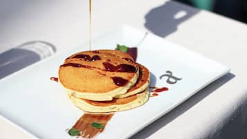 Een stapel pannenkoeken met stroop op een wit bord.