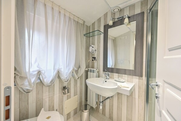 A modern bathroom with a glass shower enclosure, a white sink, and a large mirror.