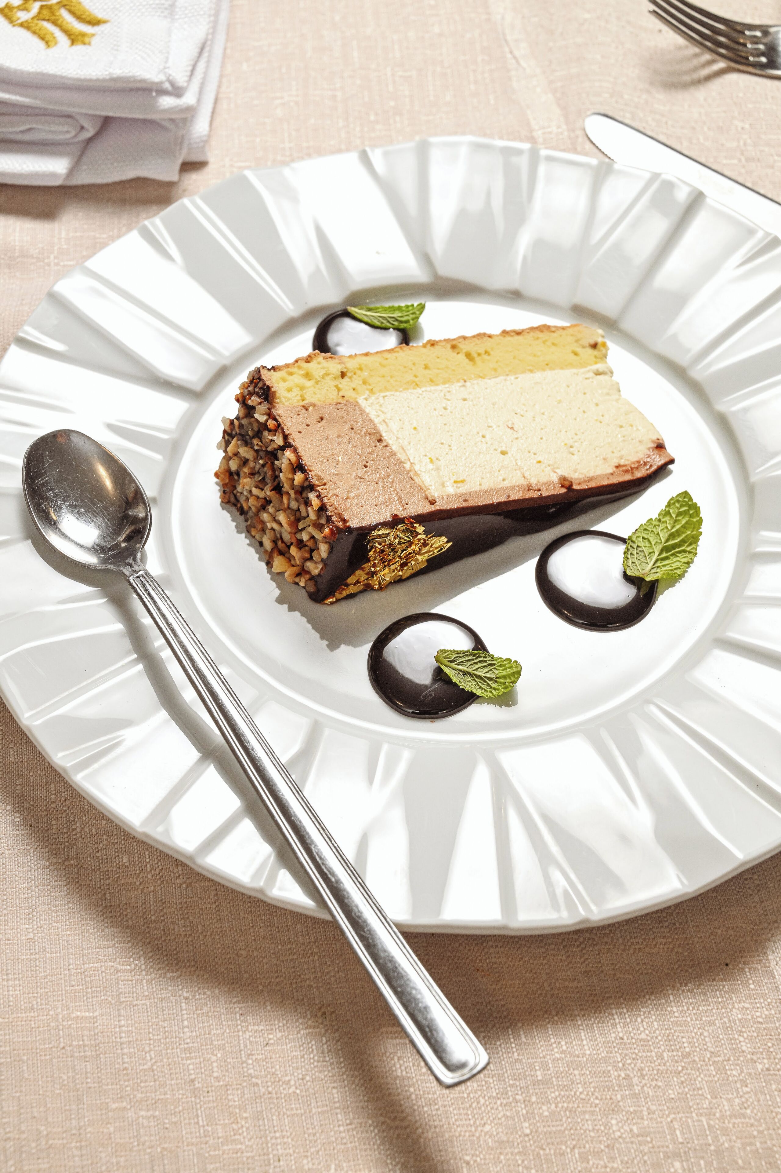 A dessert on a white plate with a spoon, garnished with mint leaves.
