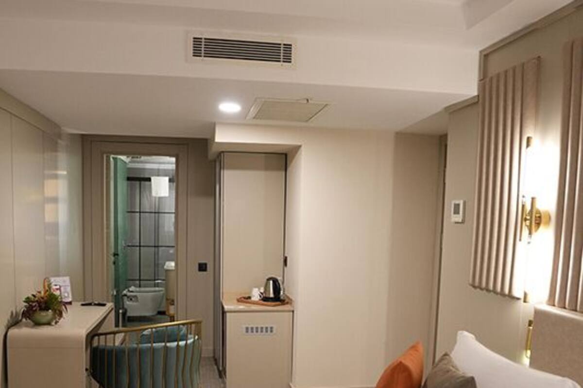 A hotel room with a bed, a desk, a chair, a mirror, and a door leading to a bathroom.