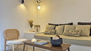 Un salon comprenant un canapé, un fauteuil, une table basse et un luminaire fixé au mur.