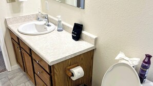 A bathroom with a toilet, sink, and mirror. There is a trash can and a bottle of hand soap. - Bright & Spacious Downtown 2 Bedroom Apt  w/ King bed! (Anchorage)