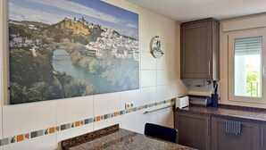A kitchen with a large cityscape mural, a tiled backsplash, granite countertops, and dark wooden cabinets.