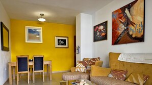 A living room with a yellow wall, a sofa, a coffee table, and two chairs.