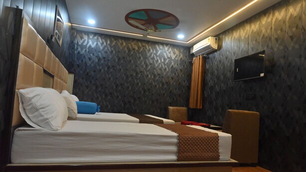 A hotel room with two beds, a ceiling fan, an air conditioning unit, and a TV on the wall. - Hotel Prince (Gorakhpur)