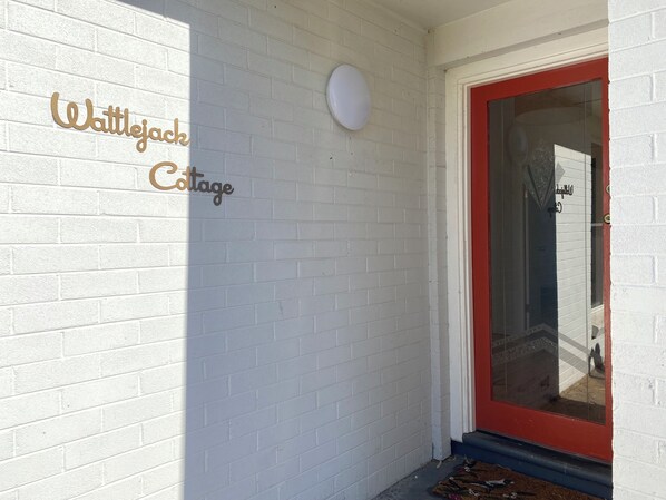 A white brick wall with a sign reading "Wattlejack Cottage." - WattleJack Cottage is the perfect base for exploring all that KI has to offer! (Kingscote)