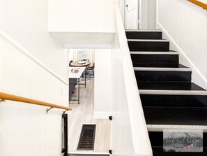 A staircase with black steps leading to a room with a dining area. - NEW OSU Reser Stadium Glamour- KING BEDS (Corvallis)