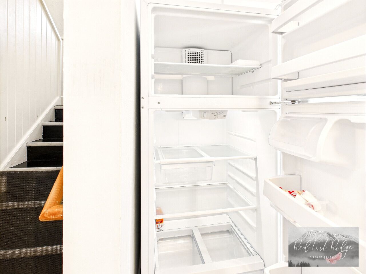 L’intérieur d’une cuisine moderne, avec un réfrigérateur encastré, un plan de travail et un escalier menant à un palier.