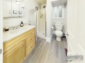 A modern bathroom with a wooden vanity, a glass shower enclosure, and a toilet.