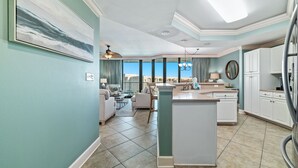 A modern kitchen with a central island, large windows, and a view of the outdoors.