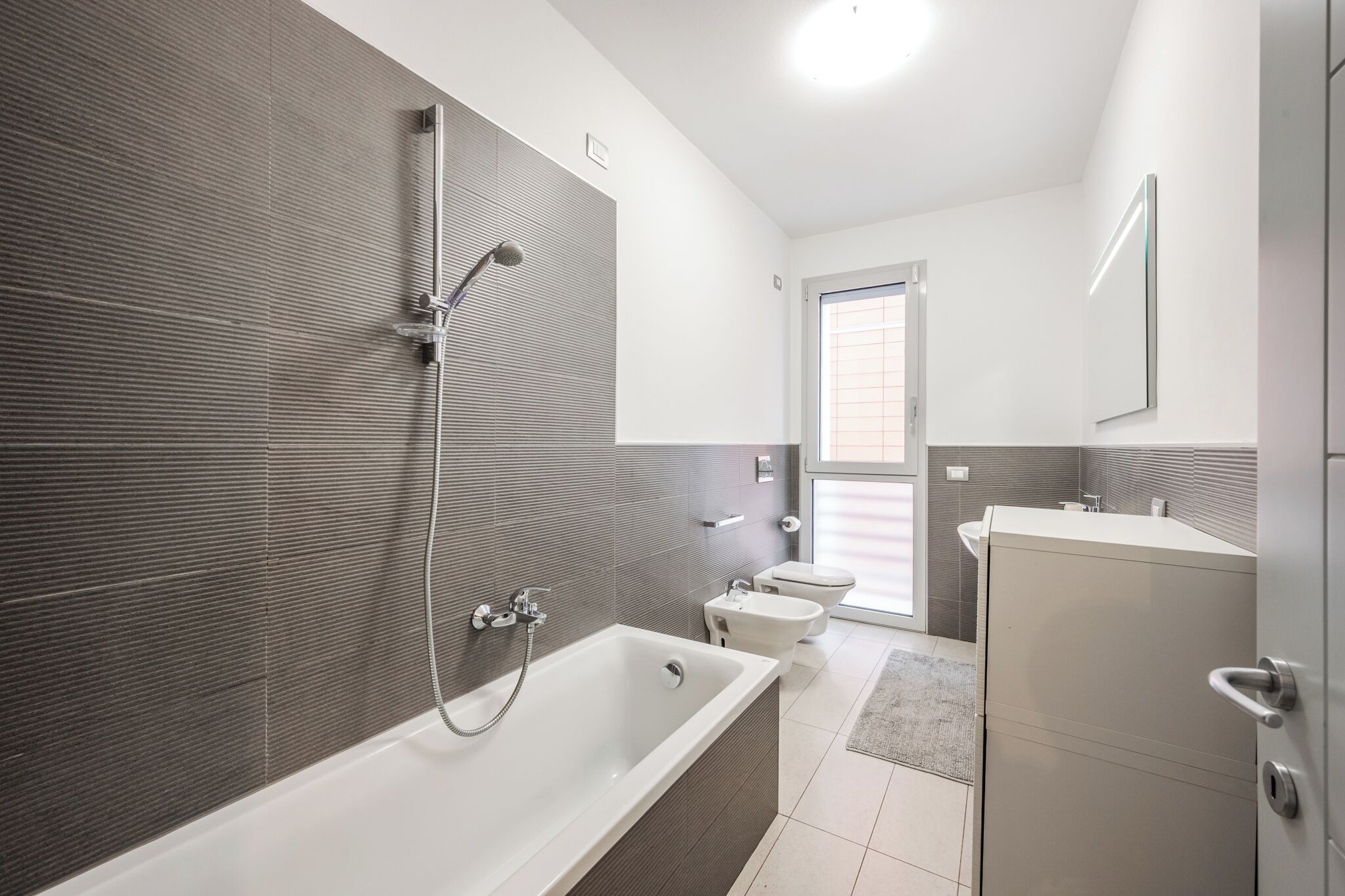 A modern bathroom with a bathtub, a shower, and a toilet.