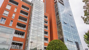 Um edifício de vários andares com fachada de tijolos e vidro, com varandas e janelas amplas.
