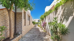 A narrow alleyway with stone pavement, flanked by buildings with brick and stucco exteriors, and lush greenery. - 4194 VSC - Terrazze Sullo Ionio by Barbarhouse (Nardò)