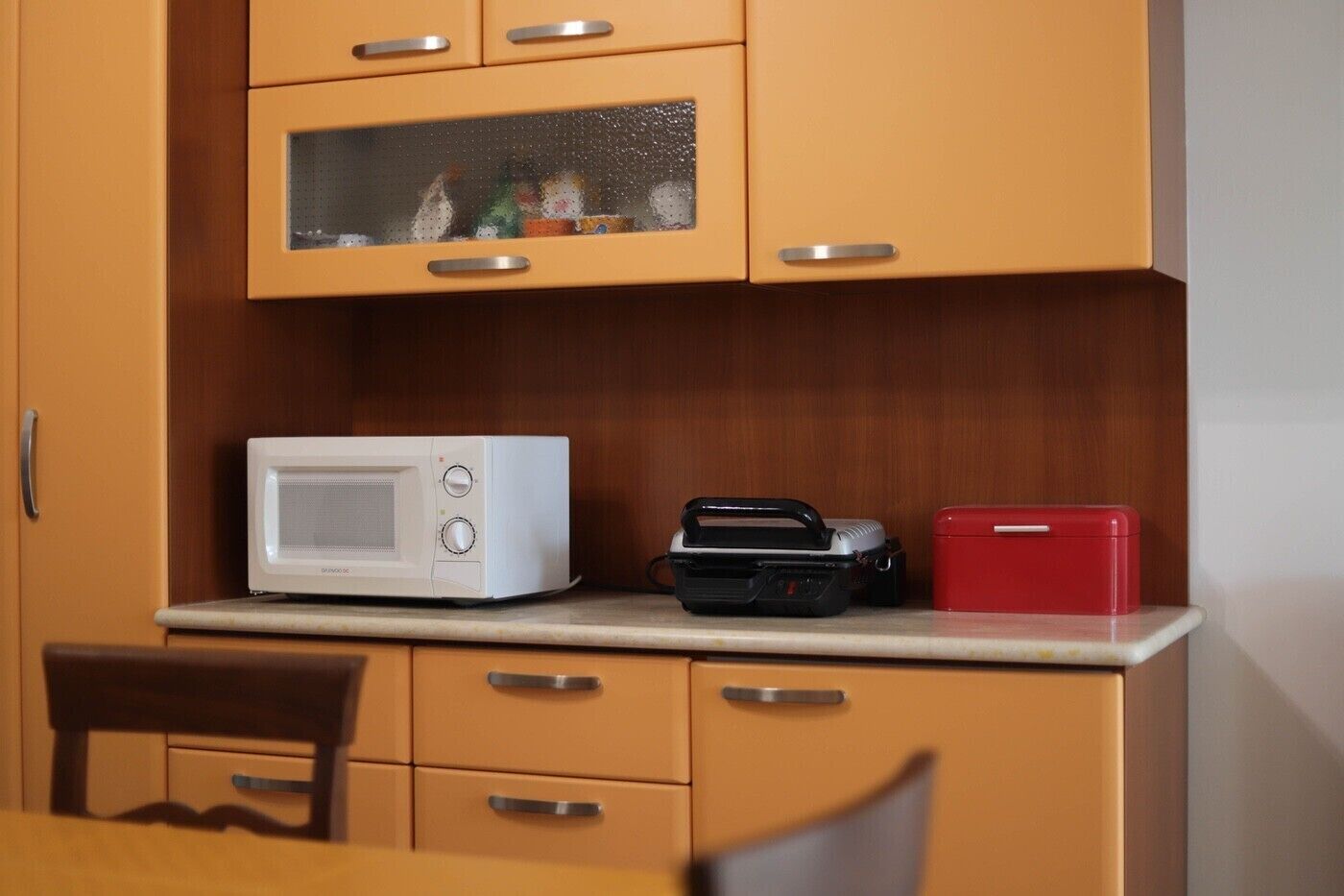 A kitchen with a microwave, a portable radio, and a red cooler on the counter.