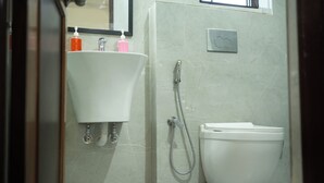 A bathroom with a white sink, a toilet, and a shower. - SM Residency (Bhubaneshwar)
