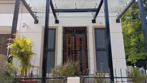 A building with a central entrance flanked by two large windows, surrounded by potted plants and a metal fence. - SM Residency (Bhubaneshwar)