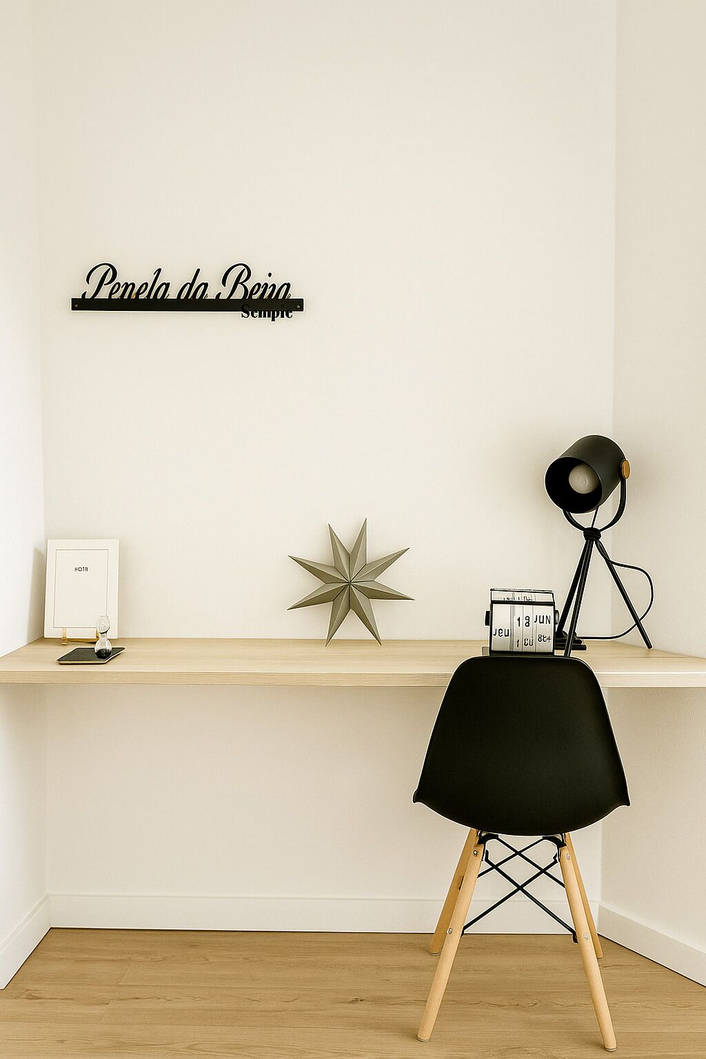 Uma composição de secretária minimalista com um adorno em forma de estrela, uma placa emoldurada e uma luminária.