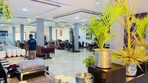 Un espace de restauration d’hôtel avec des tables et des chaises, un buffet et des plantes en pot.