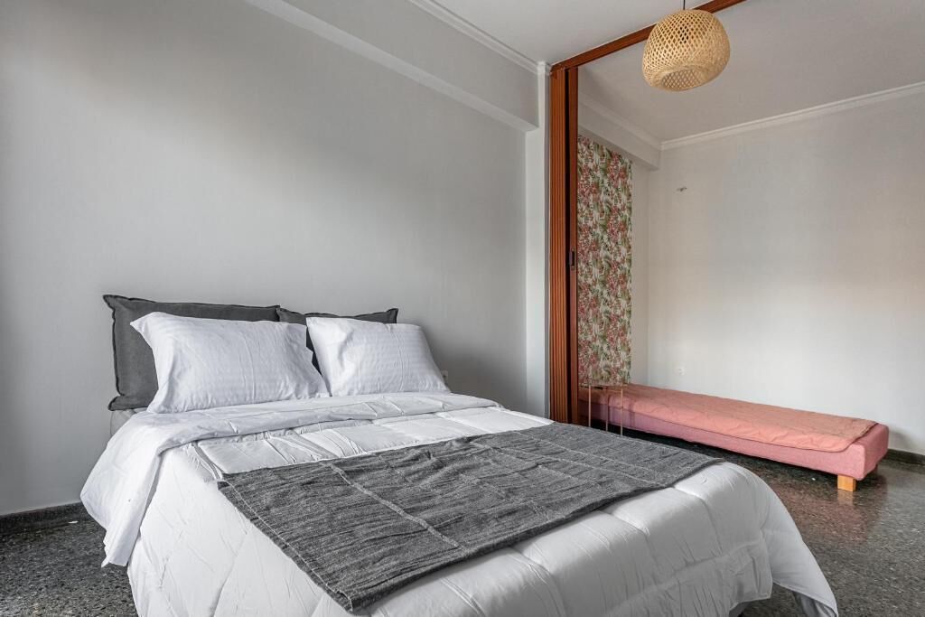 Une chambre à coucher avec un lit, un banc et un luminaire suspendu.