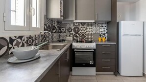 Eine Küche im modernen Stil mit einem Gaskochfeld, einem Backofen, einer Spüle und einem weißen Kühlschrank.