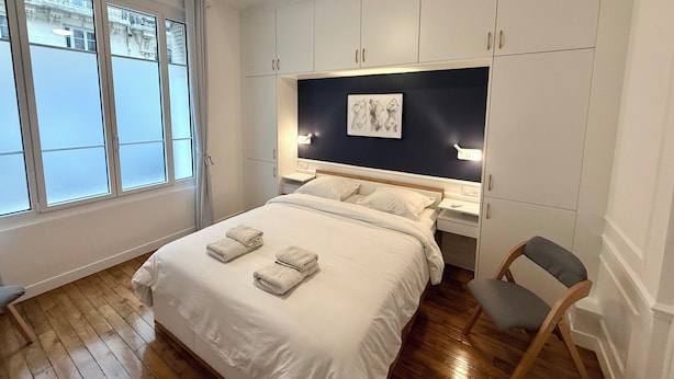 Una camera da letto con un letto, una sedia, una scrivania e una ventola a soffitto.