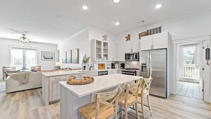 A modern kitchen with a central island, white cabinetry, and a stainless steel refrigerator. - Seagrove’s 30A Window to Heaven: Pool and Beach (Santa Rosa Beach)