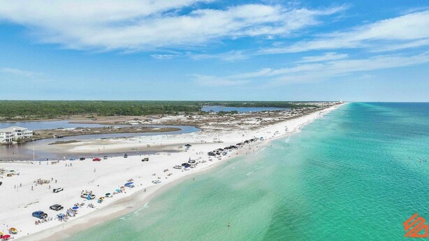 A coastal beach with a long stretch of sand, clear turquoise waters, and a few buildings in the distance. - Seagrove’s 30A Window to Heaven: Pool and Beach (Santa Rosa Beach)