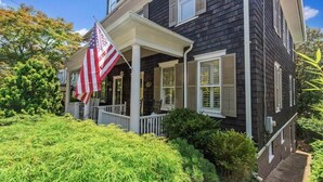 A two-story house with a porch and an American flag.