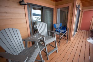 A wooden deck with two Adirondack chairs and a table, a sliding glass door, and a red door. - Ski-In / Ski-Out! Hot Tub! New Listing! Garage! (Mt. Crested Butte)