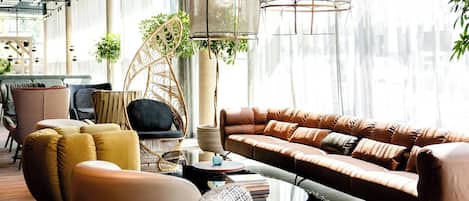A modern living room with a brown leather sofa, yellow armchairs, and wicker furniture.