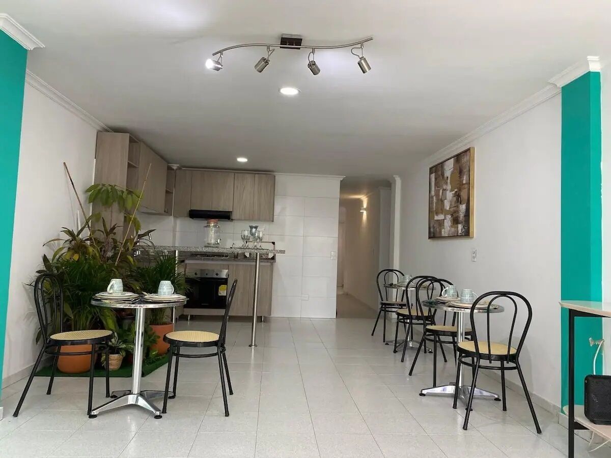 A modern kitchen with built-in appliances, a dining area with a round table and chairs, and a teal accent wall.