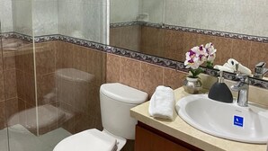 Ein modernes Badezimmer mit Duschkabine, Toilette, Waschbecken, Handtuch und Spiegel.