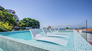 Une piscine avec des chaises longues et vue sur l’océan.