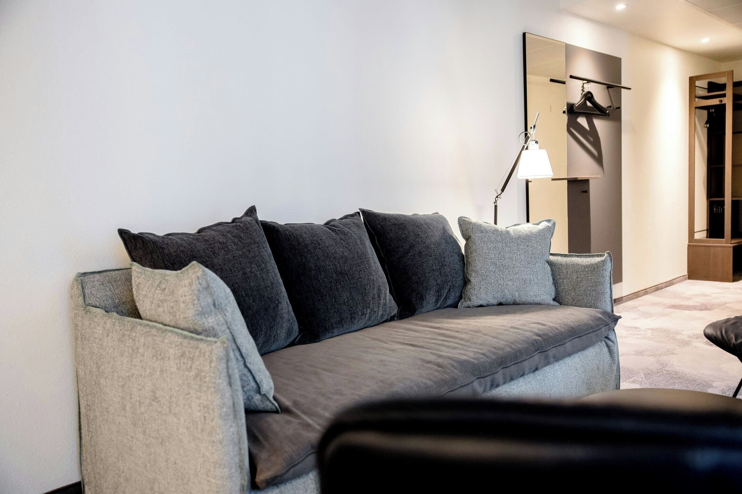 Ein modernes Wohnzimmer mit einem grauen Sofa, einer Stehlampe und einem Garderobenständer.