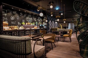 En moderne caféindretning med barområde, siddepladser og dekorative vægdetaljer.