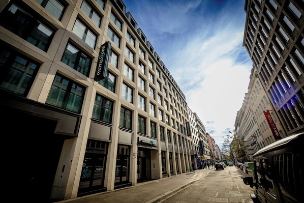 A multi-story hotel with a modern facade, large windows, and a visible sign for the Helvetia Hotel. - Motel One München-Hauptbahnhof (Munich)