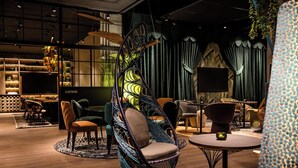 Ein moderner Lounge-Bereich mit verschiedenen Sitzgelegenheiten, darunter ein besonderer Hängekorbschaukel, mehrere Sofas und ein runder Tisch.